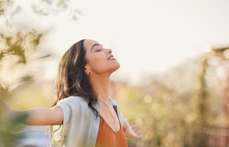 Woman looking happy and mindful, having learned how to breathe to reduce stress
