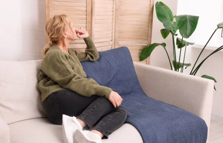 Woman sitting on a sofa looking thoughtful and sad into space