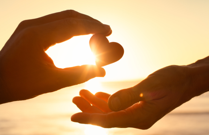 Hand giving heart to another hand