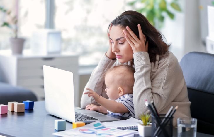 Working mom with toddler on her lap looking tired