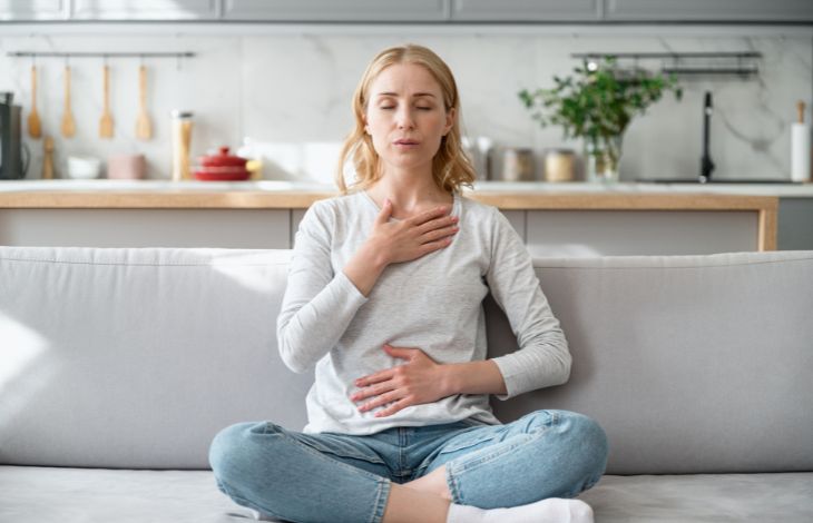 Woman sitting on couch breathing exercises for mom burnout